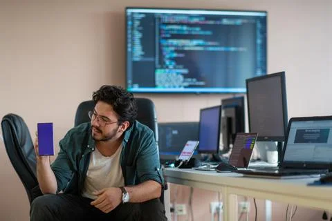 A programmer diligently testing smartphone applications Stock Photos