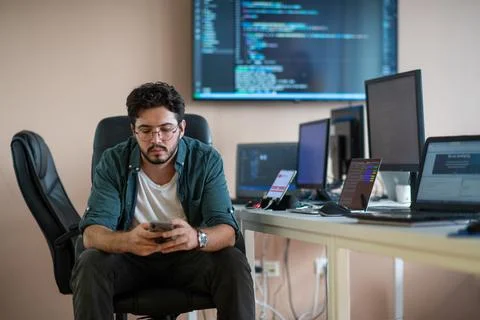 A programmer diligently testing smartphone applications 库存照片
