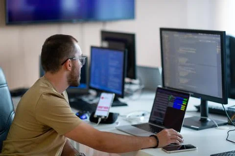 A programmer diligently testing smartphone applications while sitting in their Stock Photos