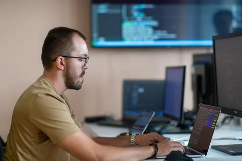 A programmer diligently testing smartphone applications while sitting in their Stock Photos