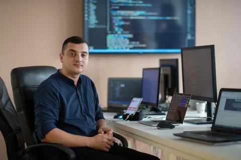 A programmer diligently testing smartphone applications while sitting in their Stock Photos