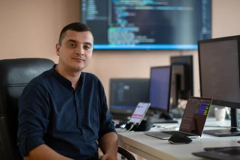 A programmer diligently testing smartphone applications while sitting in their Stock Photos