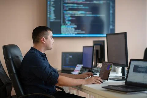 A programmer diligently testing smartphone applications while sitting in their 库存照片