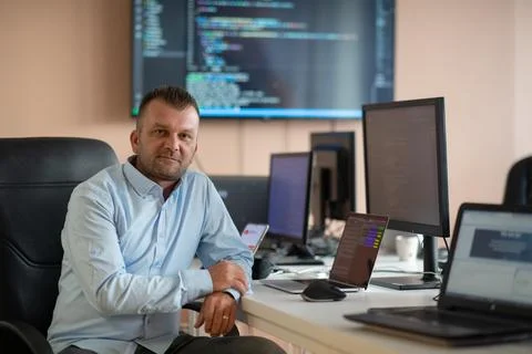 A programmer diligently testing smartphone applications while sitting in their Stock Photos