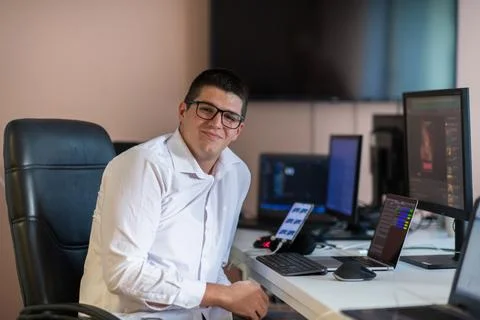 A programmer diligently testing smartphone applications while sitting in their Stock Photos