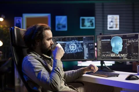 Programmer drinking coffee, chatting with awaken AI on computer Stock Photos