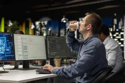 Programmer drinking coffee in startup office, coding machine learning models Stock-Fotos