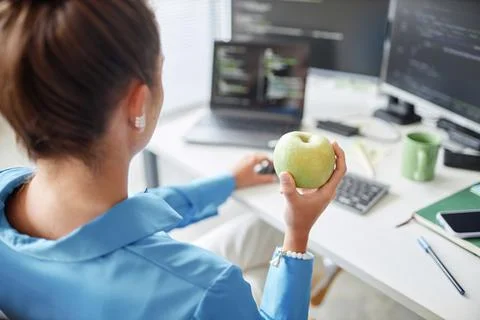 Programmer eating apple and working on computer Stock Photos