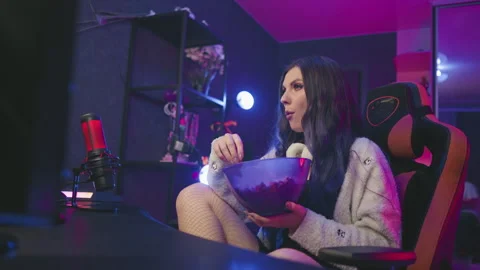Programmer eating popcorn while seated with crossed legs inside cozy studio 스톡 동영상 307459595