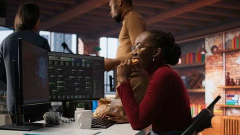Programmer eating snack at desk and coding advanced AI algorithm in startup Foto stock