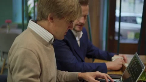 Programmer explaining code to business partner at cafe Stock Footage 142382295
