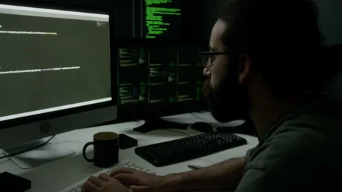 Programmer Focusing on Dual Monitors Displaying Lines of Code in Dimly Lit Room Stock-Footage 302194563