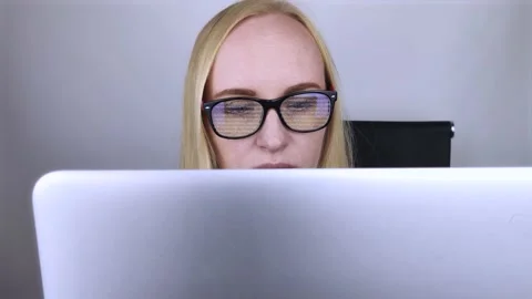 The programmer girl's glasses reflect moving lines of code. Programming, develop Stock Footage 138730625
