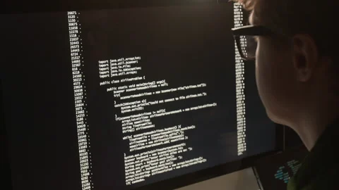 Programmer with Glasses Analyzing Code on Computer Screen Stock Footage 336718436