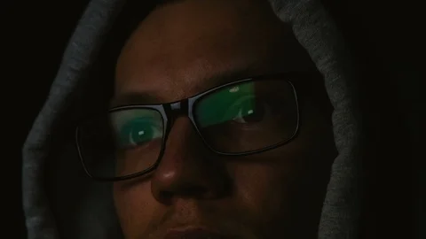 Programmer with glasses and a hood works at a computer in the dark, a reflection Stock Footage 87541827