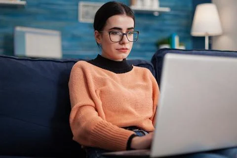 Programmer with glasses holding laptop on sofa writting code. Stock Photos