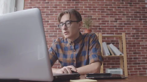 The programmer guy rubs his eyes after working at the computer. The young man Stock Footage 124964316