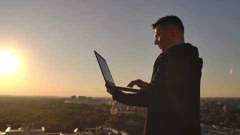 Programmer a hacker is on the roof with a laptop at sunset says error code on Stock Footage 116883155