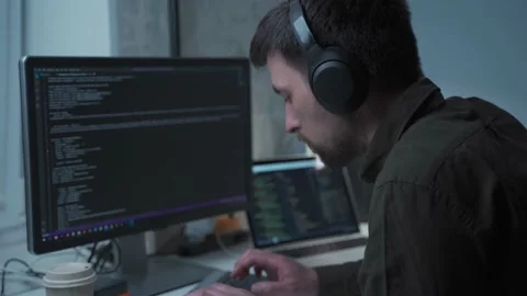 Programmer in headphones cancel noise working on new software development behind Stock Footage 153499444