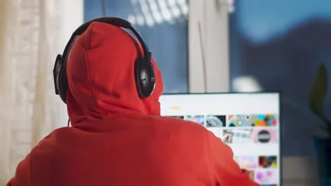 Programmer in headphones working on a computer at home, back view Stock Footage 149896126