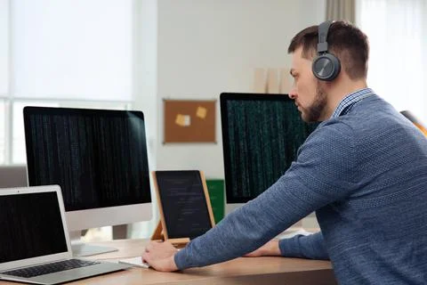 Programmer with headphones working at desk in office 写真素材