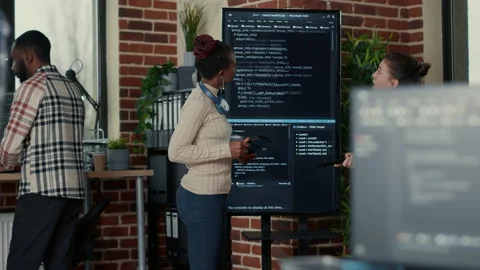 Programmer holding digital tablet analyzing code on wall screen tv while Video stock 168232523