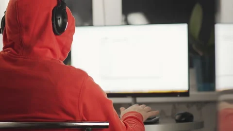 The programmer in the hood works in the home in the sitting at the monitor Stock Footage 153388072