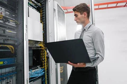  Programmer with laptop in data center room Portrait of modern young man h... Foto stock