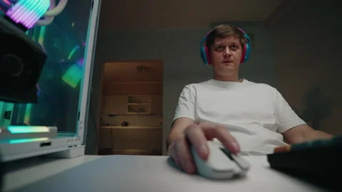 Programmer male in headphones deeply focused on coding at desktop computer in Stock Footage 317538577