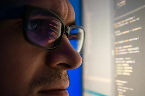Programmer, a man in front of a computer, the code is reflected in the glasses. Foto stock