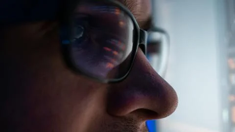 Programmer, a man in front of a computer, the code is reflected in the glasses. Stock Photos