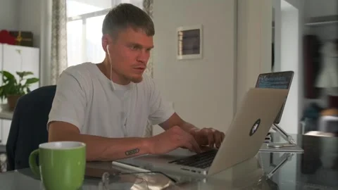 Programmer multitasks on video call, typing with tablet displaying code. Video stock 294292636