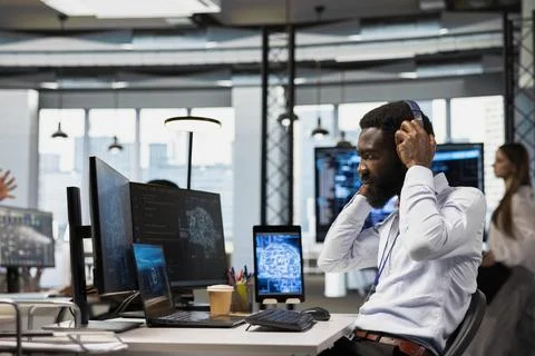 Programmer in office relies on AI to run tasks across device, listening music Foto stock