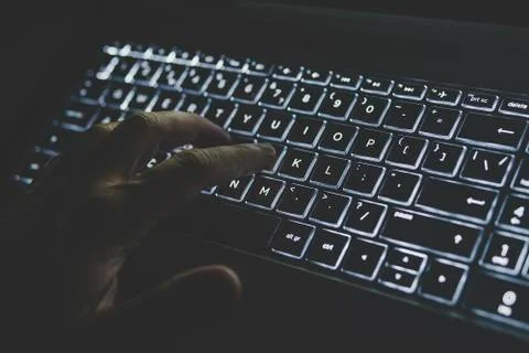 Programmer or computer hacker typing code on laptop keyboard. keypad is lit i Stock Photos