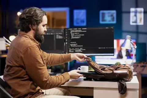 Programmer packing backpack at end of day after securing company servers Stock Photos