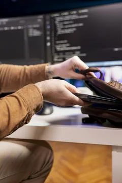 Programmer packing backpack at end of day after securing company servers Stock Photos