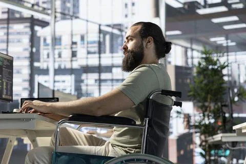 Programmer with paraplegia in inclusive workplace checking code on PC 스톡 사진