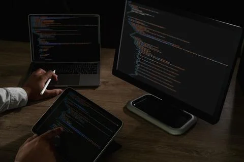 Programmer pointing at laptop screen with visible lines of code and tablet .. 스톡 사진