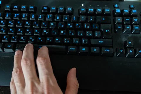Programmer pressing space bar on dusty keyboard with backlit keys Stock-Fotos
