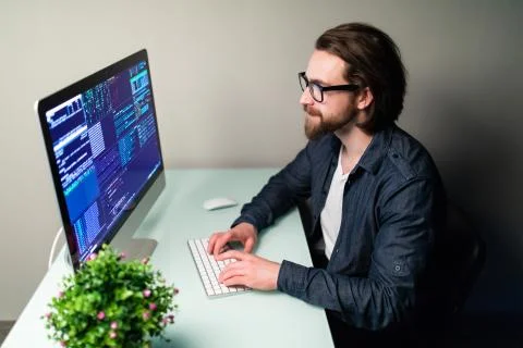 Programmer profession man writing programming code on laptop computer Stock Photos
