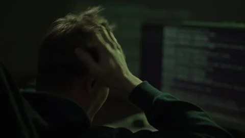 Programmer pulls at hair in dark room, staring at code on screen, late-night Stock-Footage 323471055