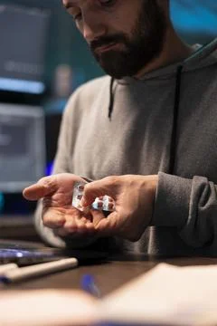 Programmer pushing pills from blister pack into palm beside laptop keyboard Stock-Fotos
