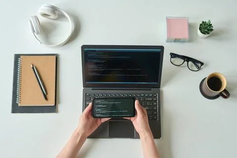 Programmer reading codes from the phone to laptop Stock Photos