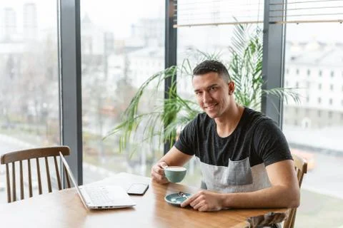 Programmer at remote job. Young man drinking coffee from a Cup. Freelancer work Stock-Fotos
