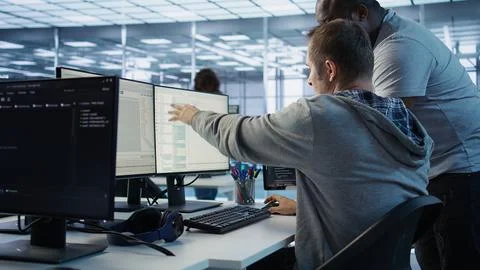 Programmer requesting help from manager while working on computer in data center Stock Photos
