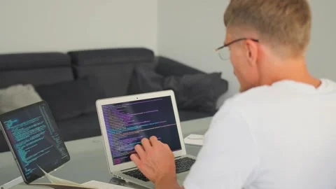 Programmer reviews and modifies code on a laptop and tablet in an office. Stock-Footage 296222987
