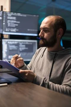 Programmer reviews paperwork with pen cap held between lips Foto stock