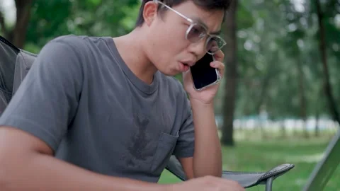 Programmer sit on a chair in a park use laptop discuss project details Stock Footage 283186703