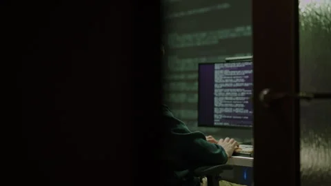 Programmer sitting in dark room, working on computer and typing on keyboard, Stock Footage 327474727