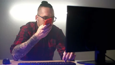 Programmer speaks an audio message to phone and looks at the computer Stock Footage 130797316